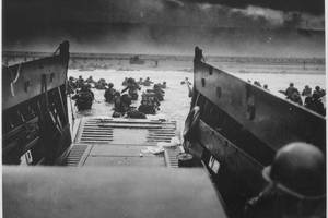 U.S. Soldiers disembark a landing craft under heavy fire off the coast of Normandy, France, June 6, 1944. (Photo Credit: National Archives U.S. Coast Guard Collection)